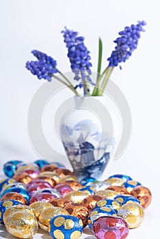 A Delfts blue vase holds blue grape hyacinth flower next to easter eggs