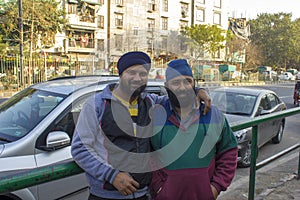 Two indian bearded men in blue turbans hugging against the background of the city road