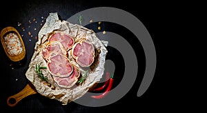 Delicacy sliced beef meatloaf with spiec salt and red pepers on a cutting board and craft paper. Meat delicacies. Top