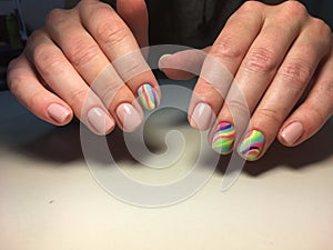 delicate beige manicure with a rainbow design on a textural background