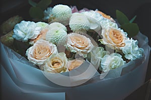 a delicate bouquet of light beautiful freshly cut roses wrapped in decorative cellophane