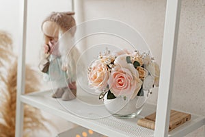 Delicate bouquet of pink flowers in a round vase on a white shelf