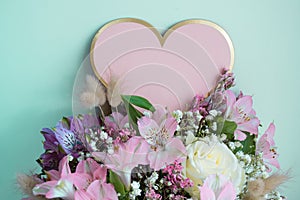 Delicate bouquet pink lilies, white roses, gypsophila. Turquoise background. Pink Heart, copy space