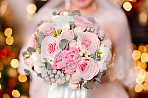 A delicate bouquet of white and pink roses in the hands of the bride