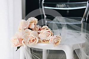 Delicate feminine picture of beautiful bouquet of roses on a chair with tulle sheer fabric, closeup or close-up
