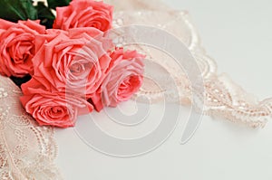 Delicate feminine theme. Pink coral roses trend color on a pale pink bra and pearl necklace on a white background. top view. close