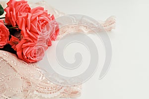 Delicate feminine theme. Pink coral roses trend color on a pale pink bra and pearl necklace on a white background. top view. close