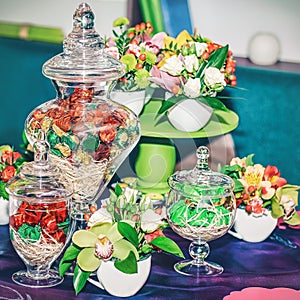 Delicate flowers and sweets in vases on the table