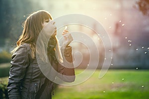 Delicate and fragile girl, sweet hope woman and nature. Blowing a dandelion.