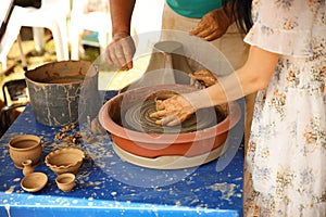 The delicate hands of a potter woman sculpt clay dishes on a potter`s wheel. Folk craft for making dishes. Creation of a ceramic