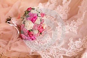 The delicate hem of the bride's dress rests on the light floor. It has ornaments, embroidery and a beautiful bouquet on