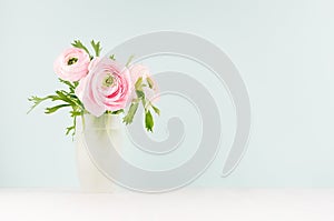 Delicate home decor with pink buttercup flowers on white wood table and mint color wall, background for design for gift, holiday.