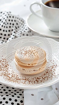 A delicate macaron with a coffee powder dusting, placed on an elegant white plate and set against the backdrop