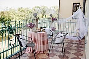 Delicate morning tea table setting with lilac flowers in Nesvizh castle, antique spoons and dishes on the table with a pink