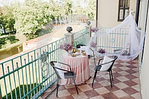 Delicate morning tea table setting with lilac flowers in Nesvizh castle, antique spoons and dishes on the table with a pink