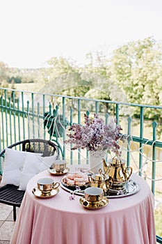 Delicate morning tea table setting with lilac flowers in Nesvizh castle, antique spoons and dishes on the table with a pink