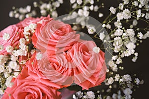 Delicate pastel pink bunch of roses decorated with small white flowers on black background as a romantic backdrop