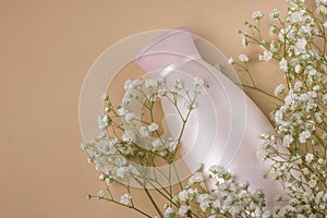 Delicate pastel pink cosmetic product with white flowers