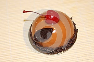 Delicate peach cheesecake decorated with red cherry and chocolate decor