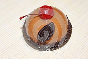 Delicate peach cheesecake decorated with red cherry and chocolate decor