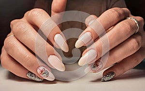 Delicate pink gel polish on long nails with a silver design. Nude manicure with a brilliant design.