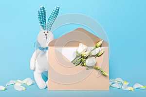 Delicate postcard layout of white flowers and bunny blue background. Holiday flat lay congratulations