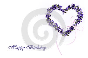 Delicate spring violets in the shape of a heart on a white background. Happy birthday