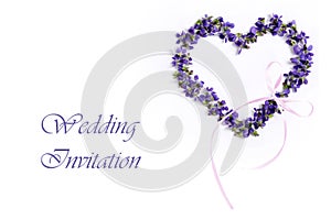 Delicate spring violets in the shape of a heart on a white background. Wedding invitation card