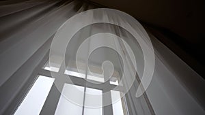 Delicate translucent curtains on a large window in a hotel. Large window with transparent tulle. Large bright window with white