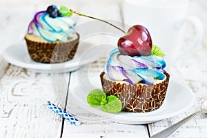 Delicate vanilla cupcakes with cream and berries on a white wooden background