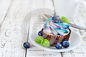 Delicate vanilla cupcakes with cream and berries on a white wooden background