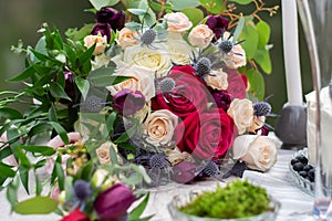 Delicate wedding bouquet with burgundy cream pink roses and feverweed, closeup