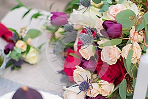 Delicate wedding bouquet with burgundy cream pink roses and feverweed, closeup