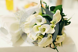 Delicate wedding bouquet made of callas lies on the white table