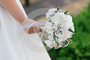 Delicate wedding bouquet with white hydrangea in the hands of the bride