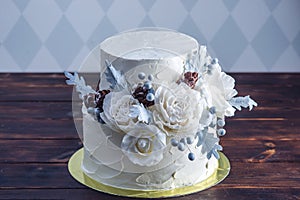 Delicate white bunk wedding cake decorated with an original design using mastic roses. Concept of festive desserts