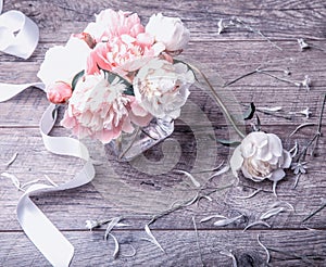 Delicate white pink peony with petals flowers and white ribbon on wooden board. Overhead top view, flat lay. Copy space