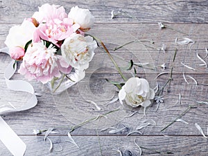 Delicate white pink peony with petals flowers and white ribbon on wooden board. Overhead top view, flat lay. Copy space