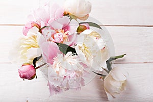 Delicate white pink peony with petals flowers and white ribbon on wooden board. Overhead top view, flat lay. Copy space. Birthday,