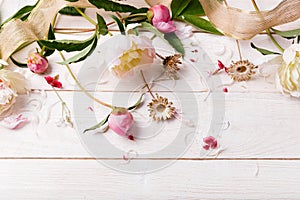 Delicate white pink peony with petals flowers and white ribbon on wooden board. Overhead top view, flat lay. Copy space. Birthday,