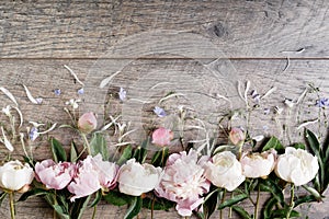 Delicate white pink peony with petals flowers and white ribbon on wooden board. Overhead top view, flat lay. Copy space. Birthday,