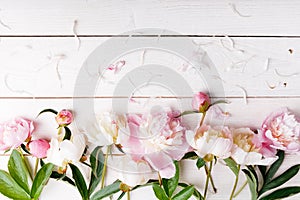 Delicate white pink peony with petals flowers and white ribbon on wooden board. Overhead top view, flat lay. Copy space. Birthday,