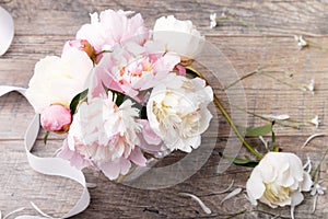 Delicate white pink peony with petals flowers and white ribbon on wooden board. Overhead top view, flat lay. Copy space. Birthday,