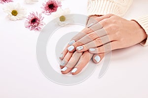 Delicate woman`s manicure on a white background.