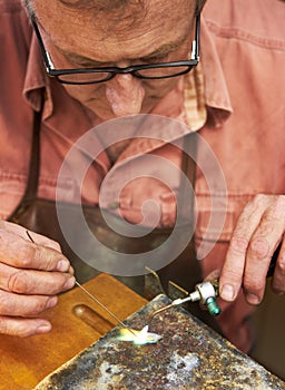This is delicate work - Jewelry manufacturing. Cropped view of a manufacturing jeweler at work with a small blow torch.
