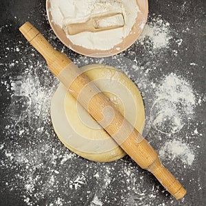 Delicate yeast dough for pies, rolling pin and flour on a gray