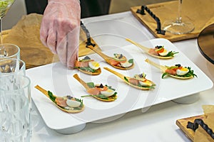 Delicates, appetizer filling with red fish, quail egg, black caviar and lime. Catering service during table decoration.