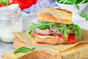 Delicatessen sandwich with beef, baked red bell peppers, arugula and horseradish sauce