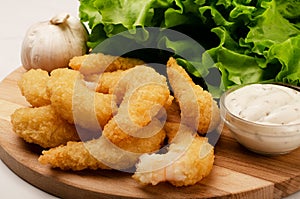 Delicatessen shrimp in breaded closeup with salad, garlic and sauce