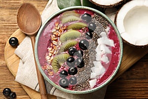 Delicious acai smoothie and fruits in bowl served on wooden table, flat lay